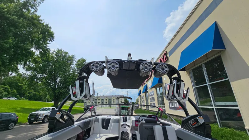 Slide: The Image of 2015 Nautique Super Air G23 boat with speakers and wakeboard racks, parked near a building. - 9