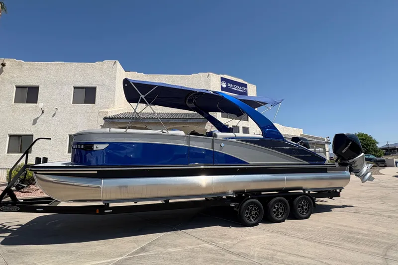 The Image of 2026 Bennington 27 RXSBAT2 pontoon boat with blue canopy on a trailer. - 0