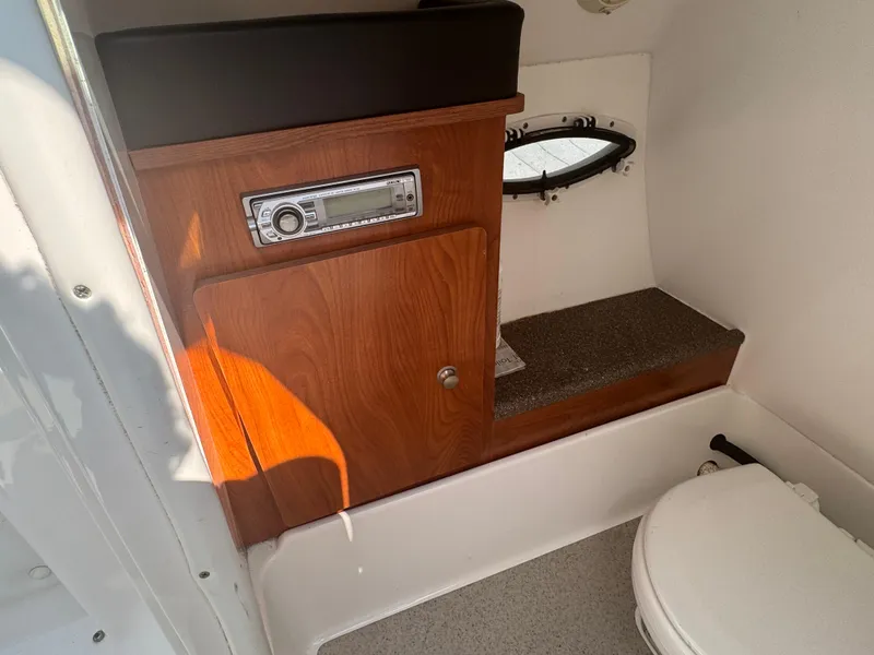 Slide: The Image of Interior of 2013 Rinker 296 Captiva Bowrider with wood paneling and compact toilet. - 11