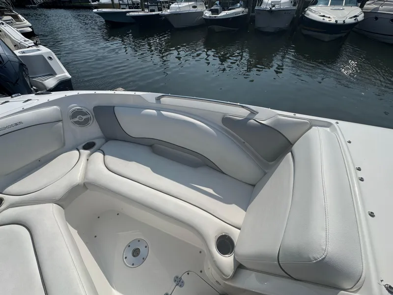 Slide: The Image of 2013 Rinker 296 Captiva Bowrider interior with white seating, docked near other boats. - 17