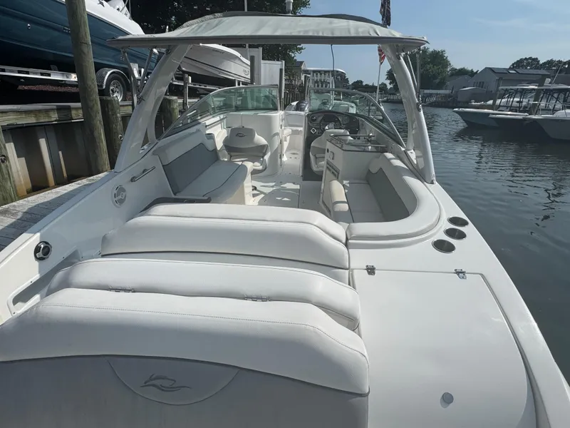 Slide: The Image of 2013 Rinker 296 Captiva Bowrider boat with spacious seating, docked by the water. - 3