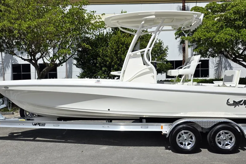 The Image of 2025 Mako 24 APEX boat on trailer, parked outdoors near trees. - 0