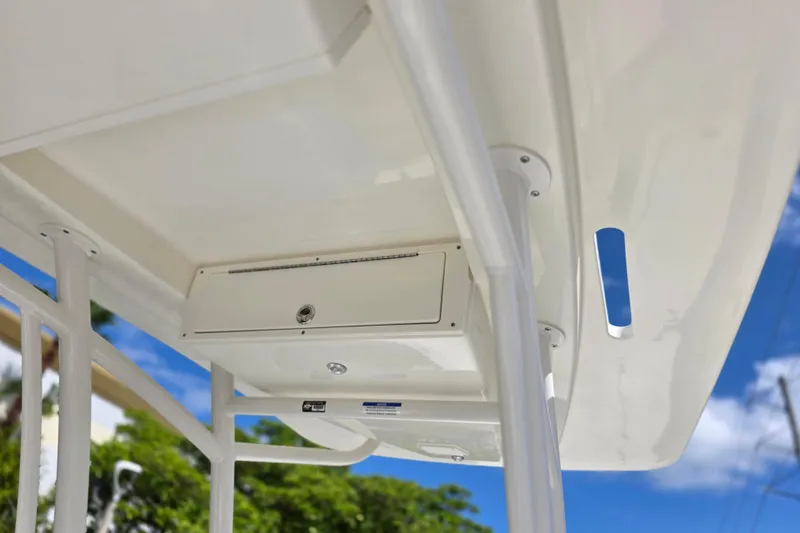 Slide: The Image of 2025 Mako 24 APEX boat canopy with storage compartment, under clear blue sky. - 12