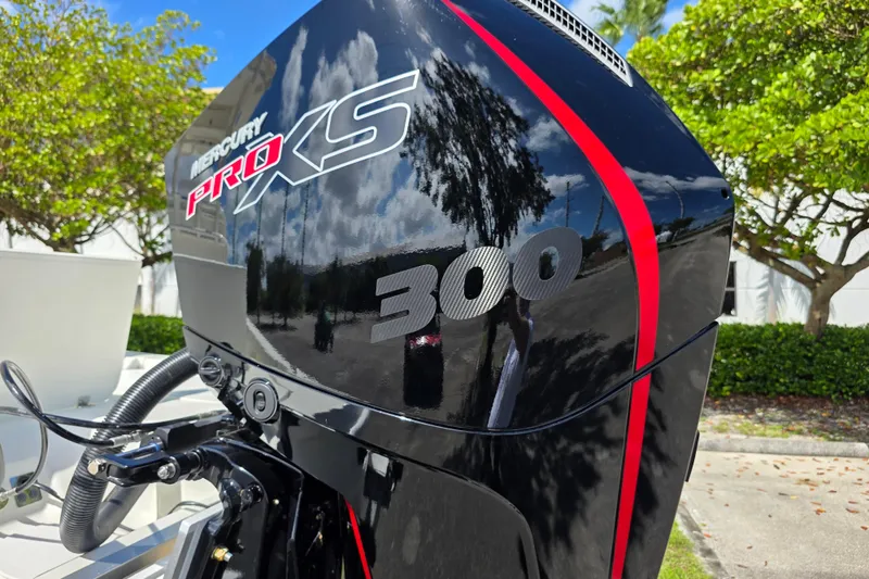 Slide: The Image of Mercury Pro XS 300 engine on 2025 Mako 24 APEX boat, outdoors with trees. - 19