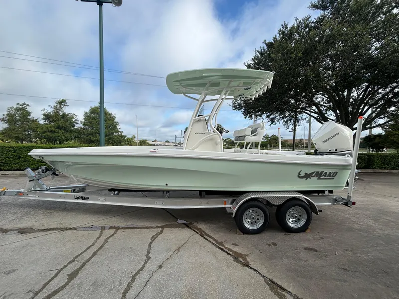 The Image of 2025 Mako 24 APEX boat on trailer, parked outdoors, featuring sleek design and Mercury engine. - 0