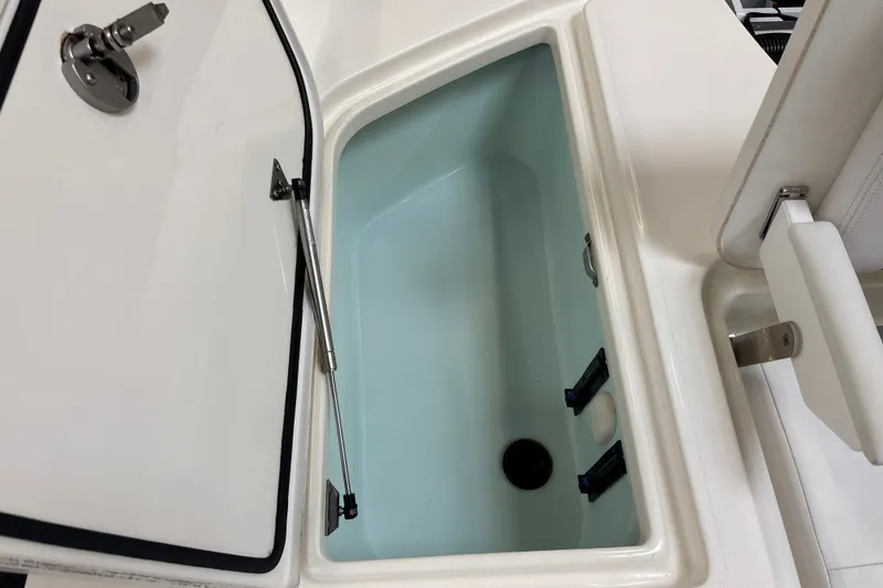 Slide: The Image of Open storage compartment on 2025 Mako 24 APEX boat, featuring hydraulic lift support. - 39