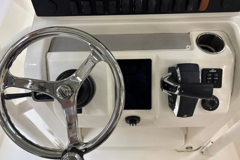 Slide: The Image of Steering console of 2025 Mako 24 APEX boat with controls and cup holder. - 28