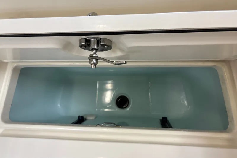 Slide: The Image of Livewell compartment in 2025 Mako 24 APEX boat, featuring a secure latch and drain. - 41