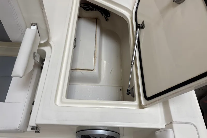 Slide: The Image of Open storage compartment on 2025 Mako 24 APEX boat, featuring white interior and hydraulic support. - 38