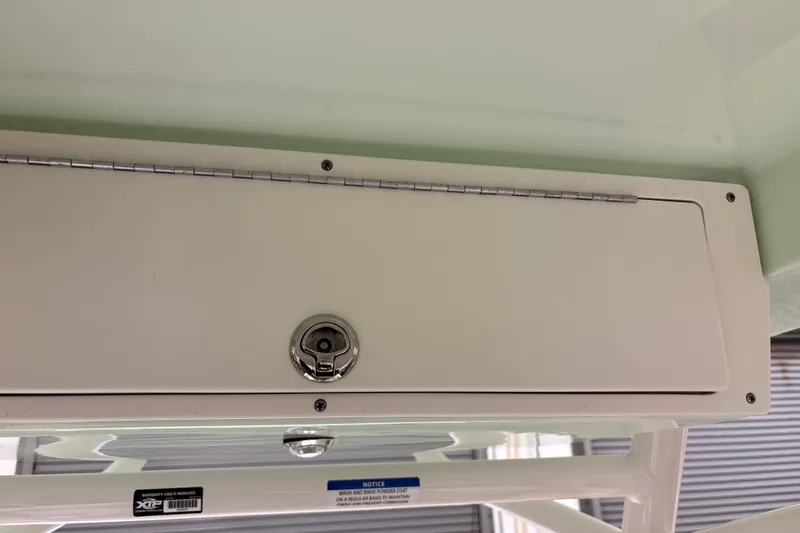 Slide: The Image of Storage compartment on a 2025 Mako 24 APEX boat, featuring a secure lock mechanism. - 36