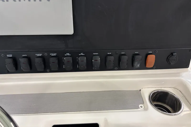 Slide: The Image of Control panel of 2025 Mako 24 APEX boat with labeled switches and cup holder. - 27