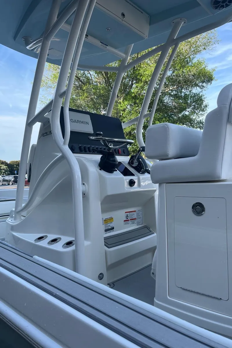 Slide: The Image of 2025 Mako 24 APEX boat console with Garmin navigation, white seating, and rod holders. - 2
