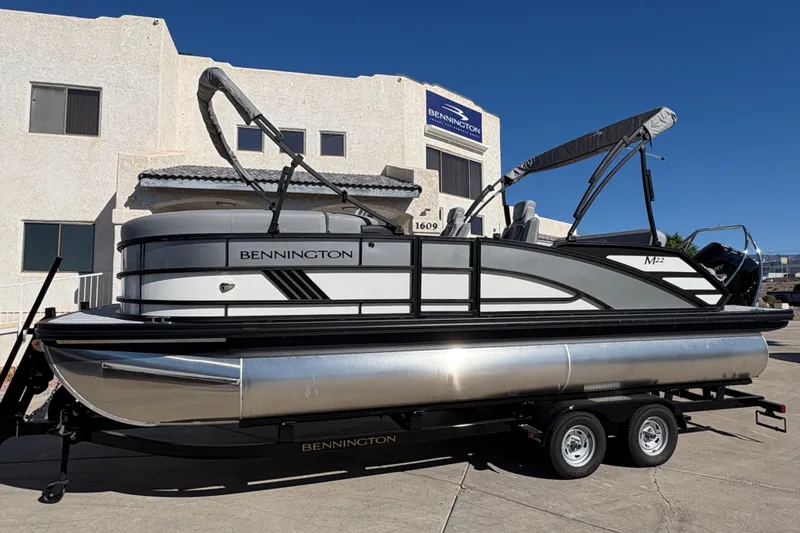 The Image of 2026 Bennington 22 MSB pontoon boat on trailer, parked outside a building. - 0