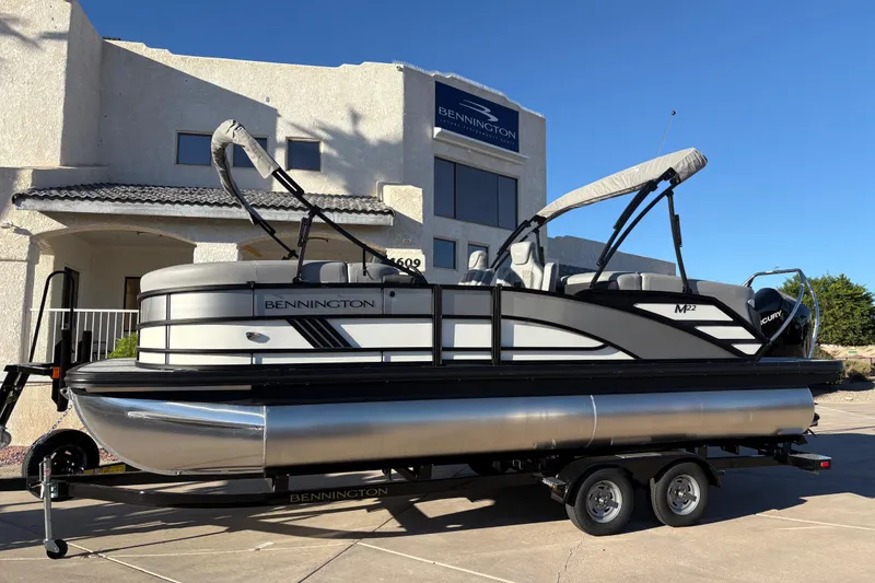 The Image of 2026 Bennington 22 MFB pontoon boat on trailer, parked outside dealership. - 0