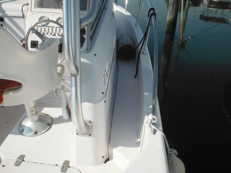 Slide: The Image of 2002 Pro-Line 23 Walk boat interior with steering wheel and seating, docked by the water. - 10