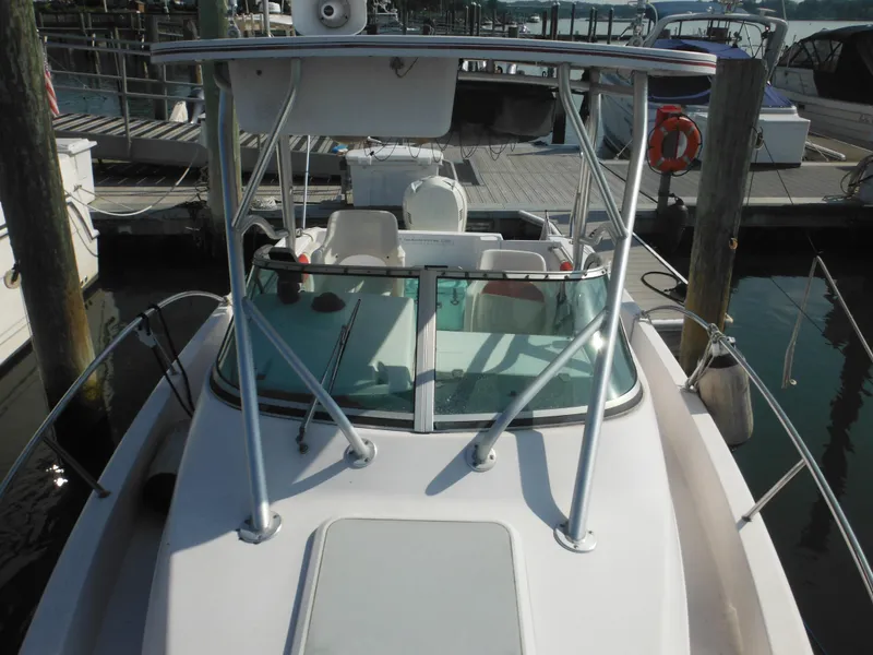 Slide: The Image of 2002 Pro-Line 23 Walk boat docked at marina, featuring a spacious deck and windshield. - 13
