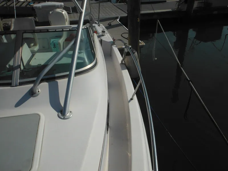 Slide: The Image of 2002 Pro-Line 23 Walk boat docked, showing deck and railing details. - 16