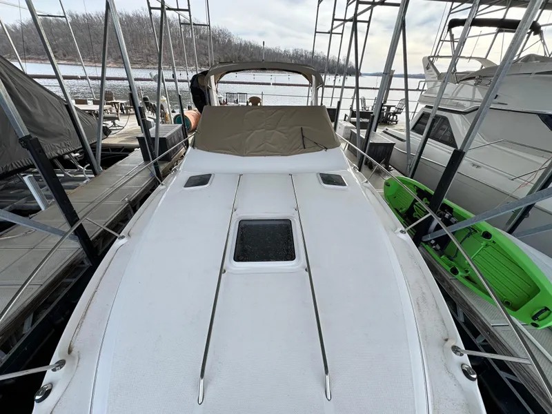 Slide: The Image of 2001 Sea Ray 310 Sundancer docked, covered, with green kayaks nearby. - 3