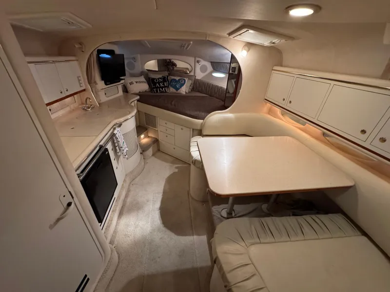 Slide: The Image of 2001 Sea Ray 310 Sundancer cabin interior with kitchenette, seating, and cozy sleeping area. - 5