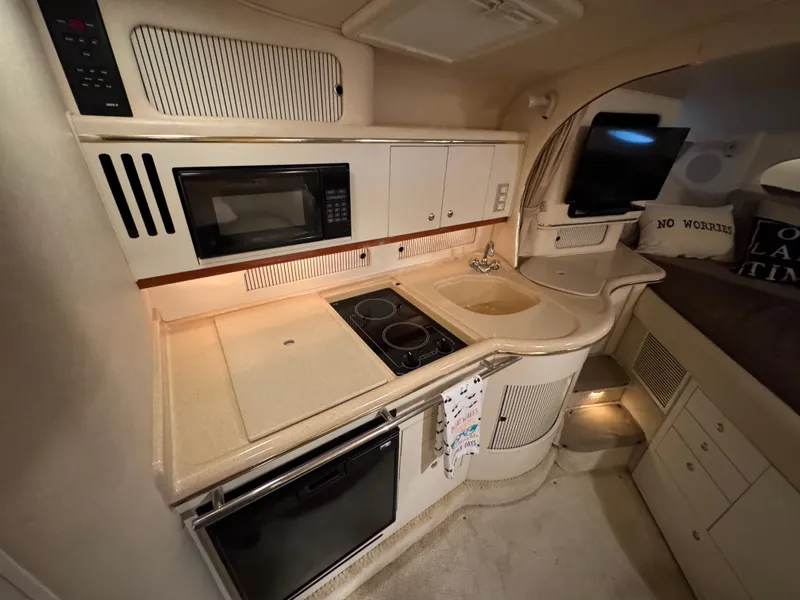Slide: The Image of 2001 Sea Ray 310 Sundancer interior kitchen with microwave, stove, and sink. - 9