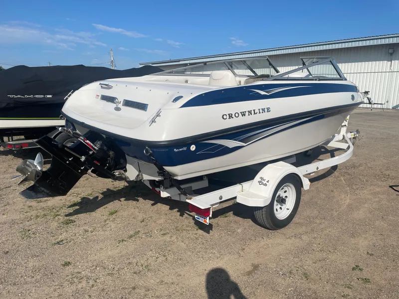 Slide: The Image of 2002 Crownline 180 BR boat on trailer, parked outdoors under clear blue sky. - 14