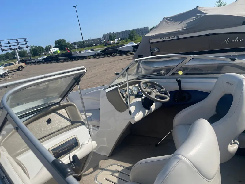 Slide: The Image of 2002 Crownline 180 BR boat interior with steering wheel and seating, parked outdoors. - 17