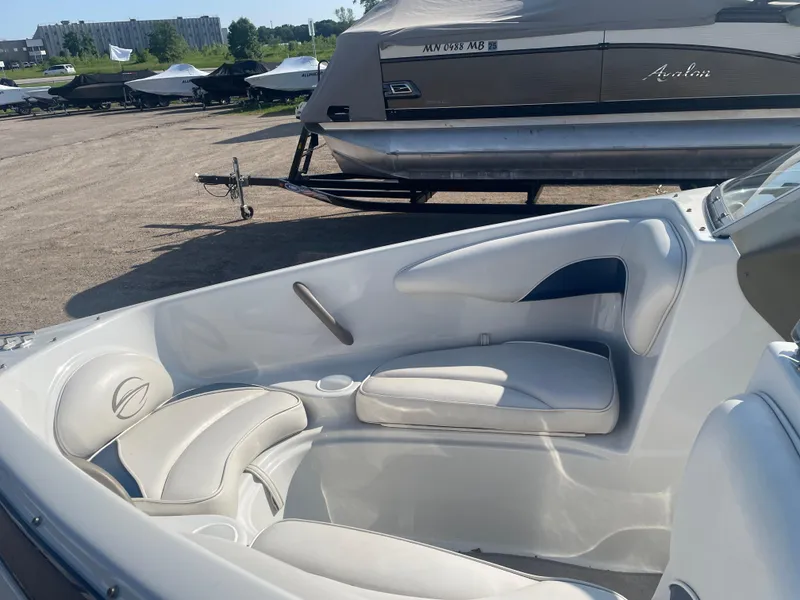 Slide: The Image of 2002 Crownline 180 BR boat interior with white seating, parked outdoors. - 18