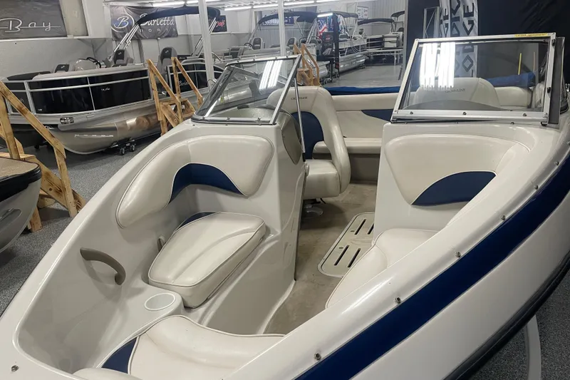 Slide: The Image of 2002 Crownline 180 BR boat interior with white and blue seating, displayed in a showroom. - 4