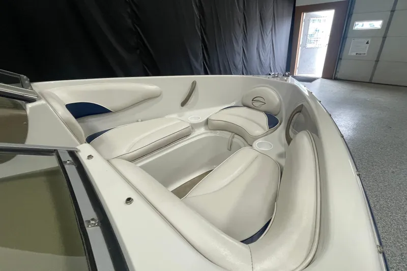 Slide: The Image of 2002 Crownline 180 BR boat interior with white cushioned seating in a showroom. - 7