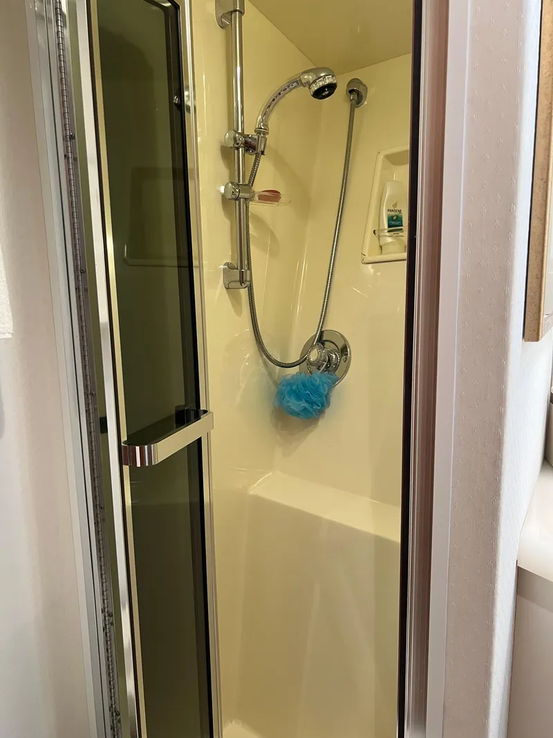 Slide: The Image of Shower area inside a 1995 Viking Sports Yacht, featuring a handheld showerhead and glass door. - 46