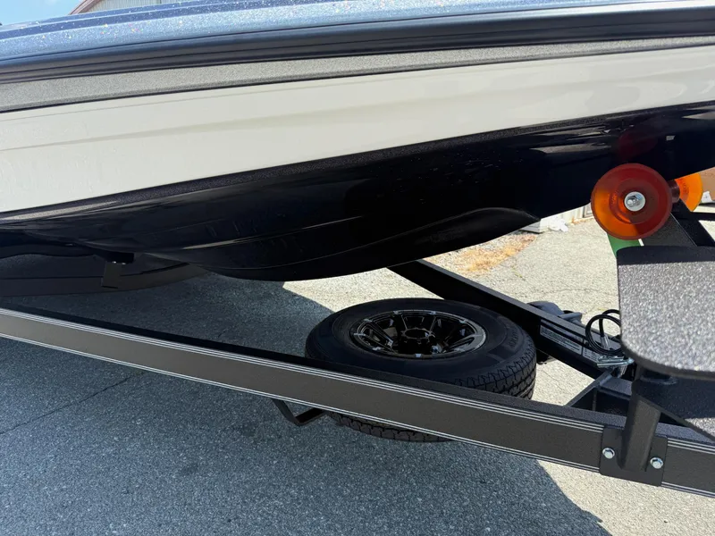 Slide: The Image of 2026 Skeeter ZXE20 boat trailer with orange rollers and black tire on pavement. - 32