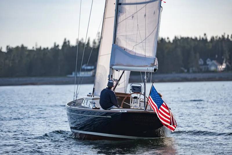 Slide: The Image of Sailing on a 2006 Morris M36 Daysailer with American flag, serene waters, and forested shoreline. - 10