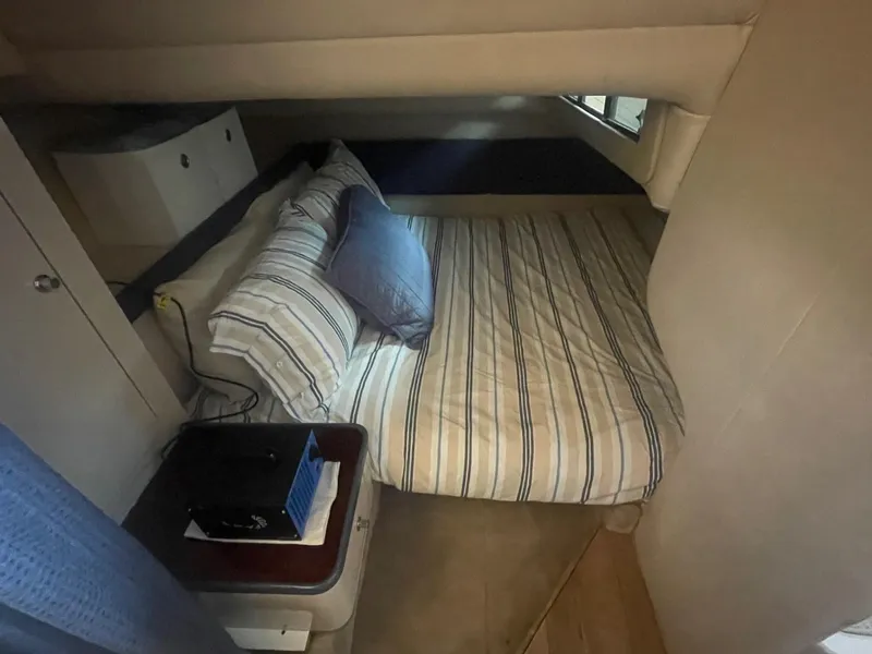 Slide: The Image of Cozy cabin interior of 1996 Regal Commodore 402 with striped bedding and side table. - 12