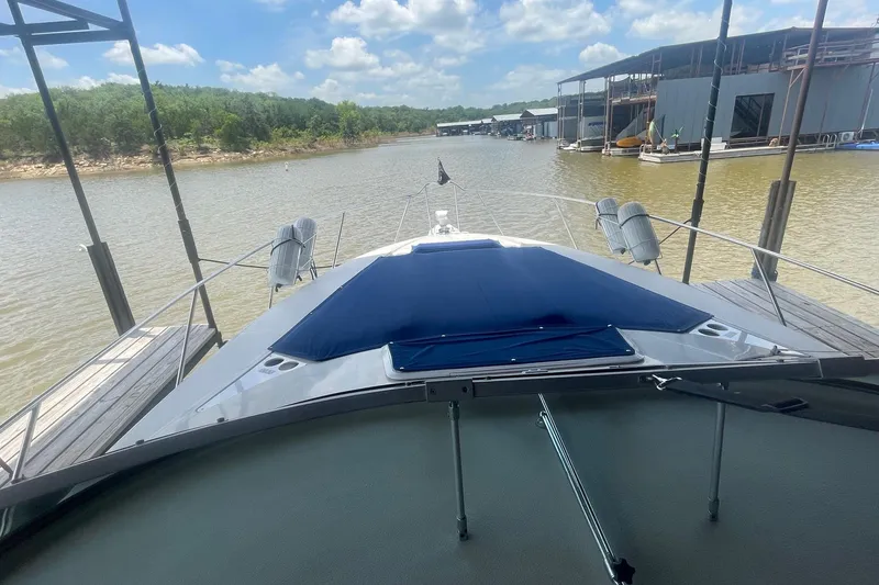 Slide: The Image of 1996 Regal Commodore 402 yacht docked on a serene lake under a partly cloudy sky. - 2