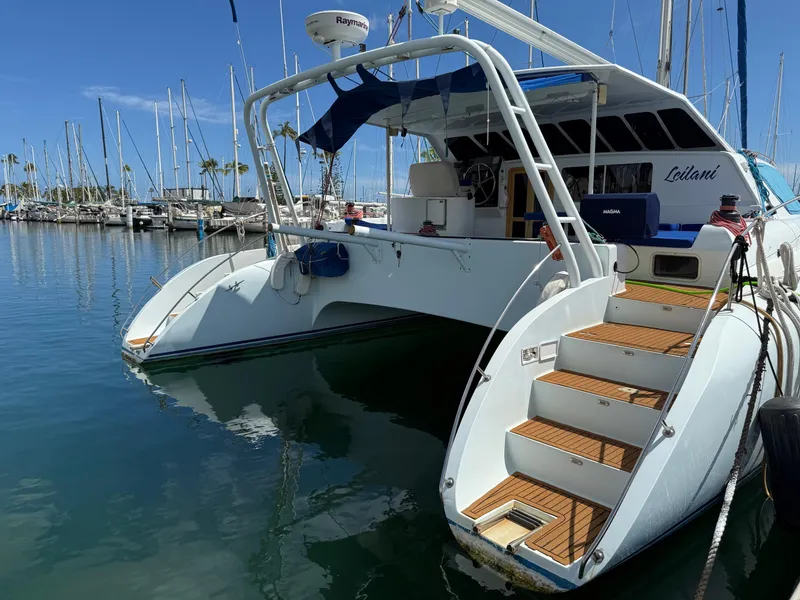 Slide: The Image of Luxury performance catamaran docked at marina, 2005 model, with elegant wooden steps and sleek design. - 27