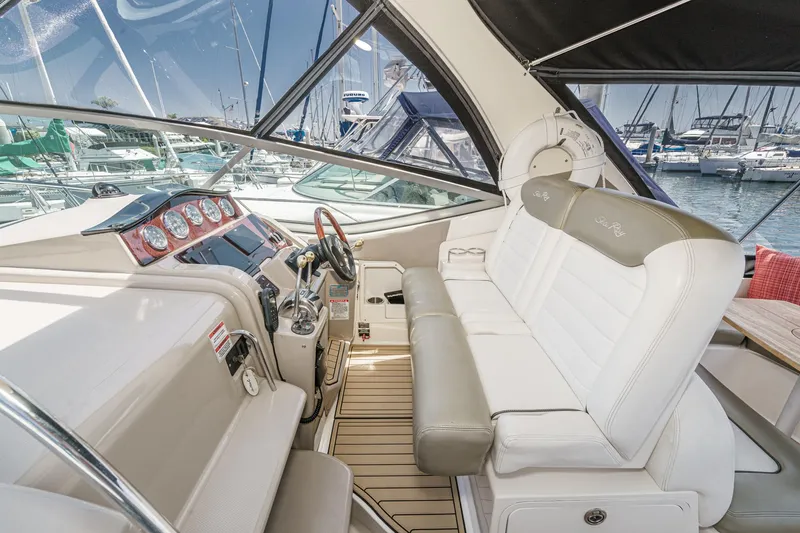 Slide: The Image of 2007 Sea Ray 310 Sundancer cockpit with white seating and control panel, docked at marina. - 15
