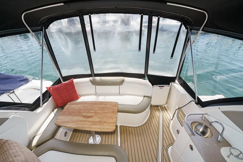 Slide: The Image of 2007 Sea Ray 310 Sundancer cockpit with seating, table, and sink, overlooking water. - 9