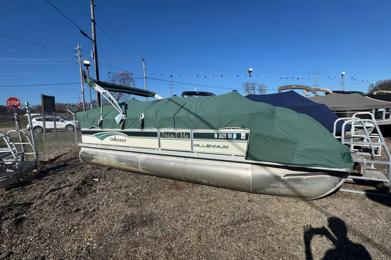 Slide: The Image of 2003 Odyssey MILLENIUM pontoon boat with green cover, parked outdoors on gravel. - 11
