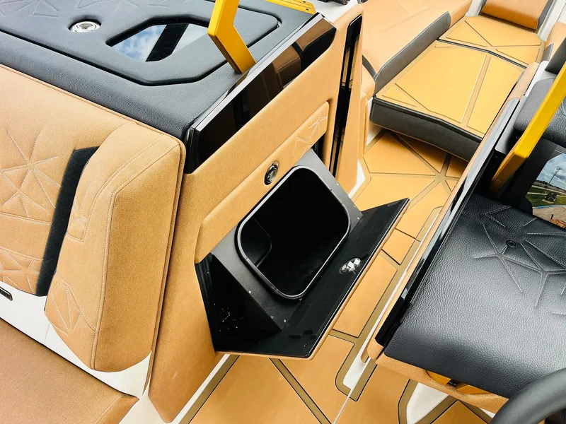 Slide: The Image of 2026 Nautique Super Air Nautique G25 Paragon interior with tan and black seating, open storage compartment. - 24