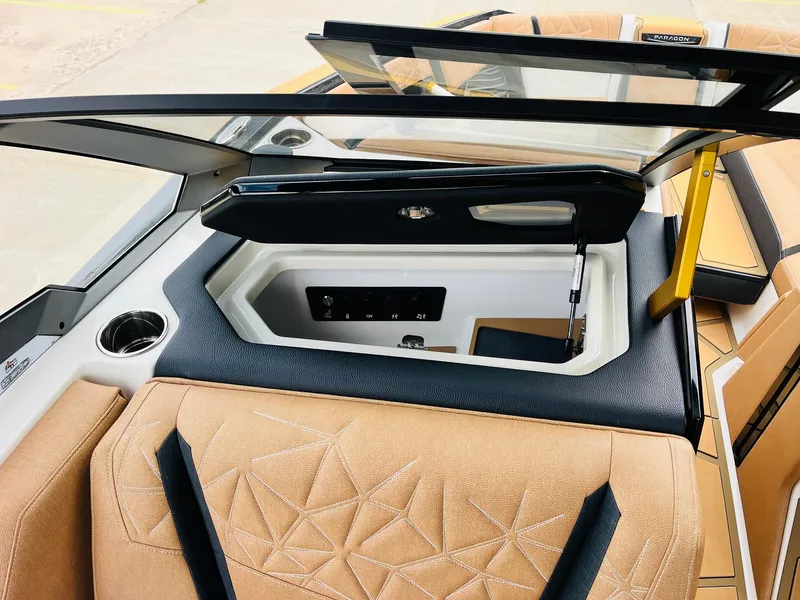 Slide: The Image of 2026 Nautique Super Air Nautique G25 Paragon interior with tan upholstery and storage compartment. - 27