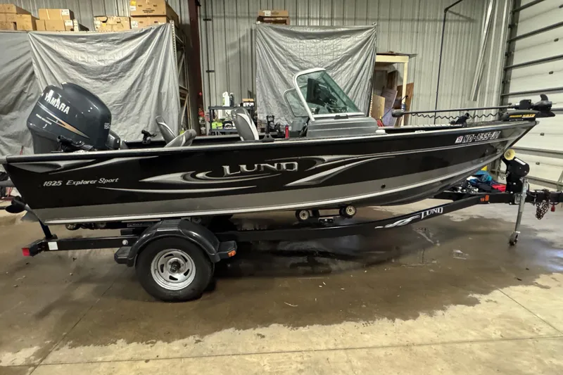 Slide: The Image of 2010 Lund 1825 Explorer boat in a garage, featuring a Yamaha motor. - 0