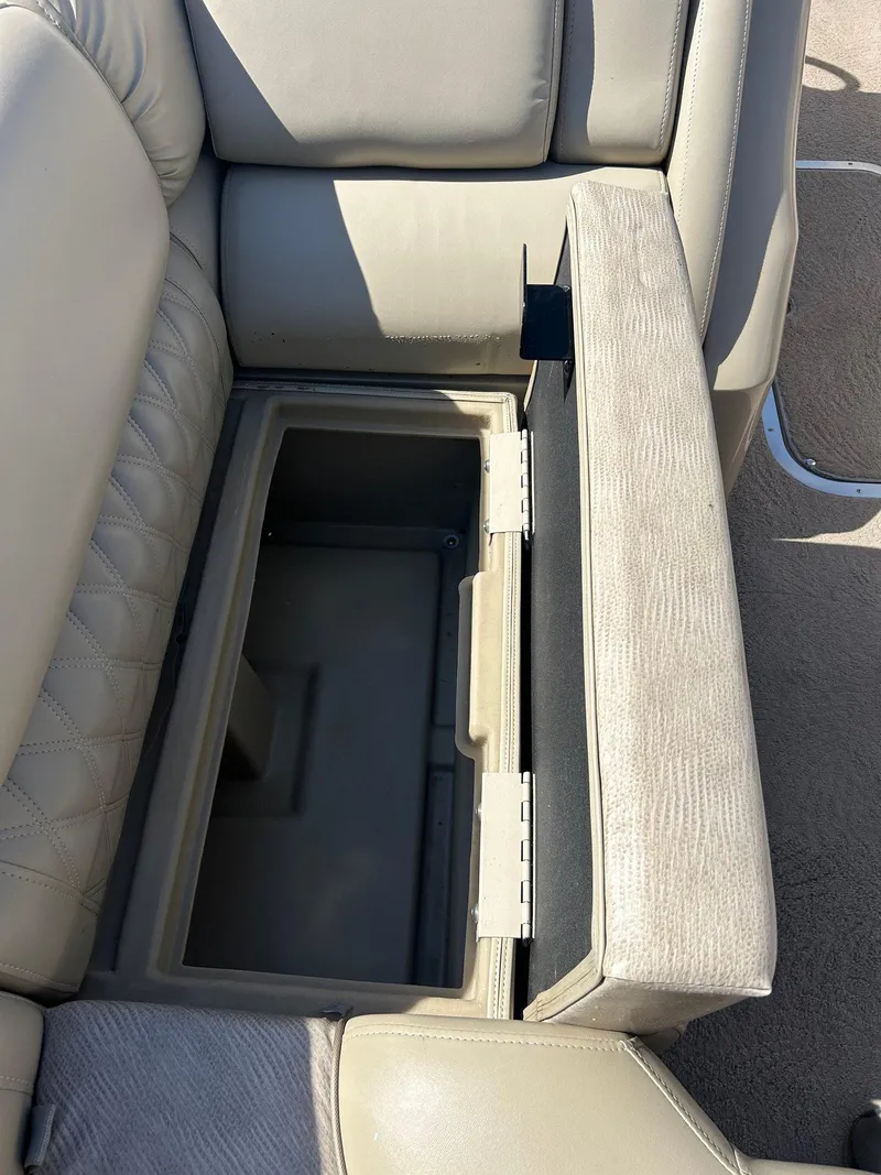 Slide: The Image of Open storage compartment in 2012 Bennington 2250RCL boat seat, showcasing beige upholstery. - 21