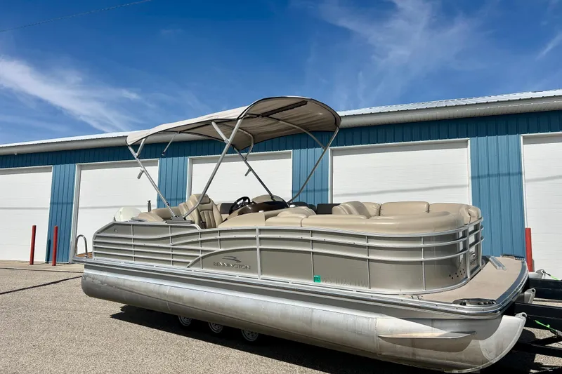 Slide: The Image of 2012 Bennington 2250RCL pontoon boat with canopy, parked near blue storage units. - 47