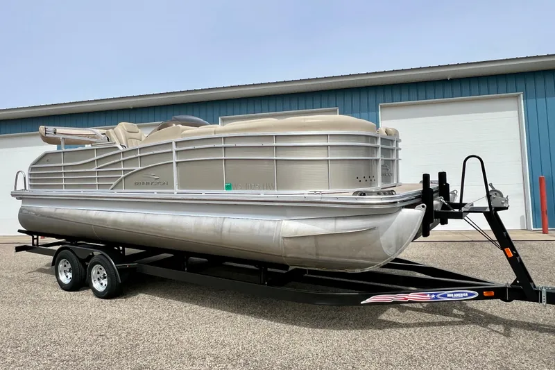 Slide: The Image of 2012 Bennington 2250RCL pontoon boat on trailer, parked outside blue building. - 48