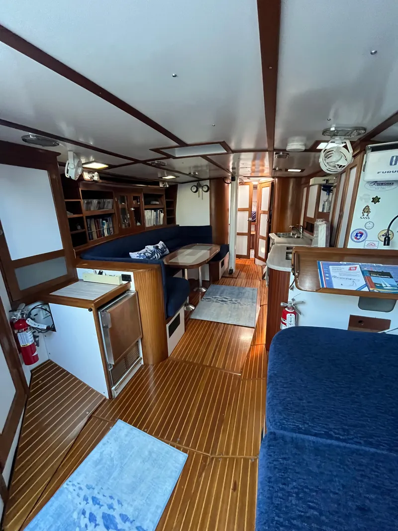 Slide: The Image of Interior of a 1976 Frers Custom yacht with wooden flooring and blue seating. - 12