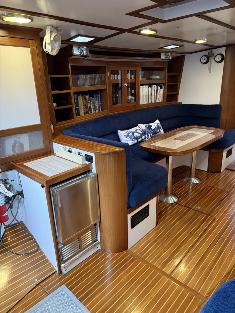 Slide: The Image of Luxurious 1976 Frers Custom yacht interior with blue seating, wooden table, and built-in bookshelves. - 15