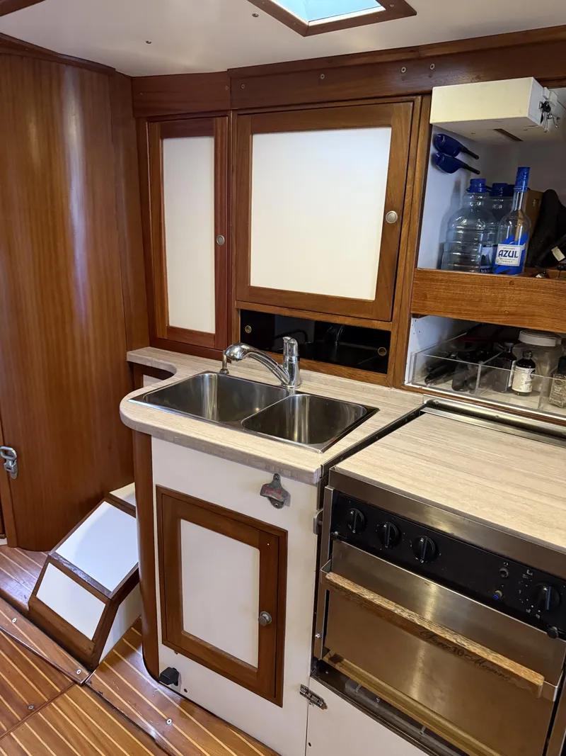 Slide: The Image of 1976 Frers Custom yacht kitchen with wooden cabinets, sink, and stove. - 19