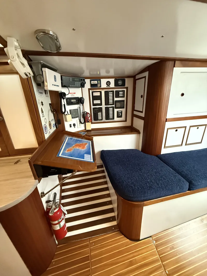 Slide: The Image of Interior of 1976 Frers Custom yacht with navigation station and blue cushioned seating. - 22