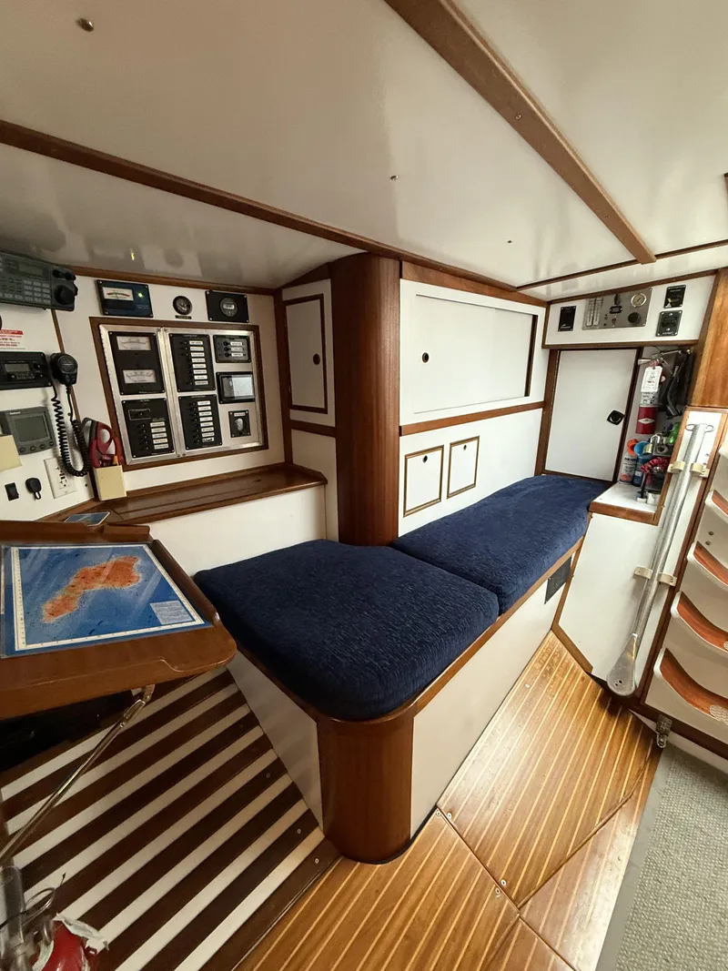 Slide: The Image of 1976 Frers Custom yacht interior with navigation station, blue cushioned seating, and wooden flooring. - 23