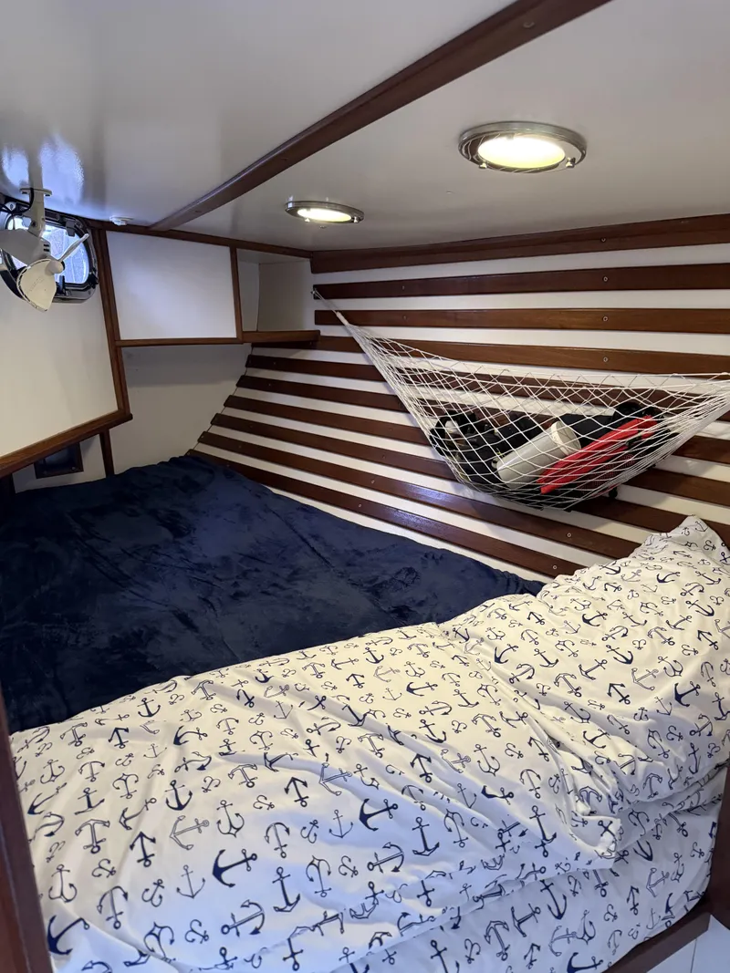 Slide: The Image of Cozy cabin interior of 1976 Frers Custom boat with nautical-themed bedding and storage hammock. - 28